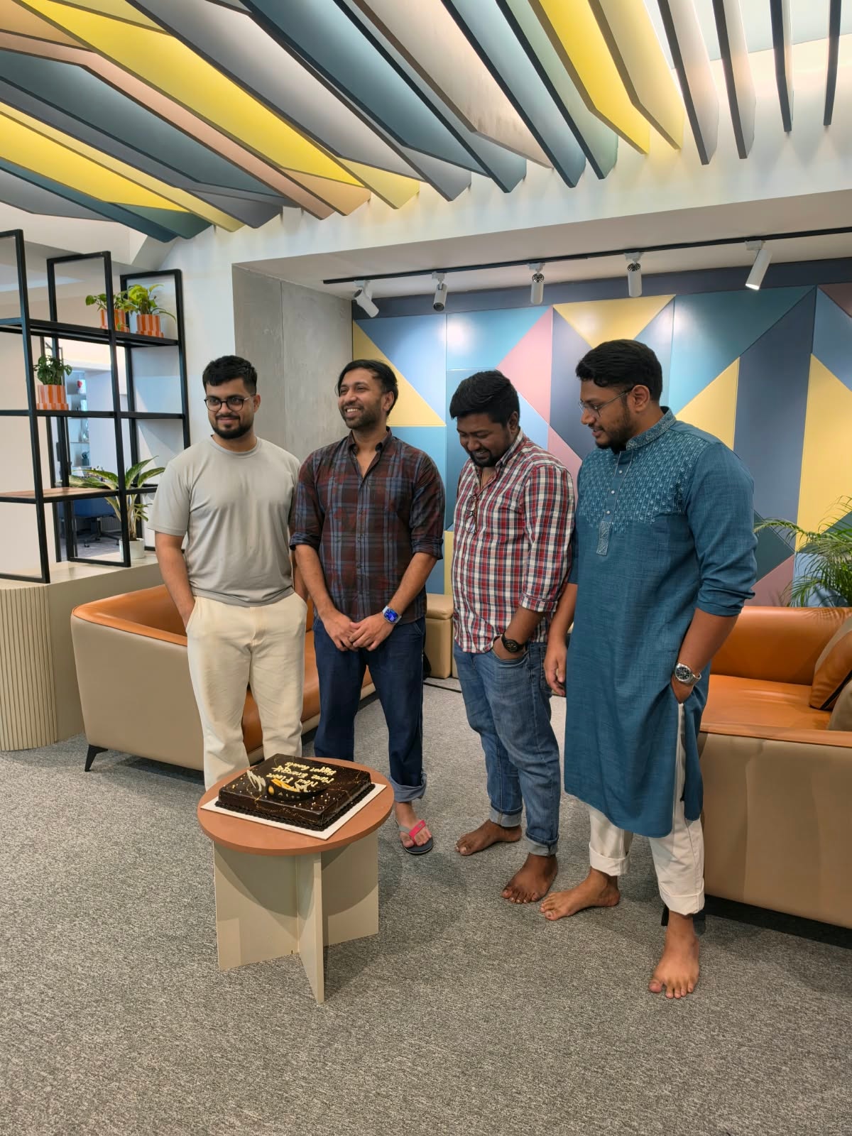 IMPIT colleagues gathered around a celebration cake in the office lounge