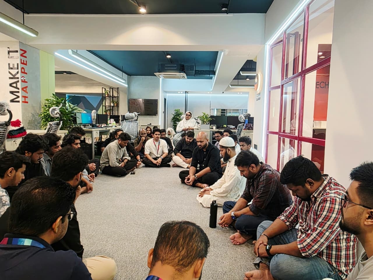 IMPIT team seated together for dua at the new office opening